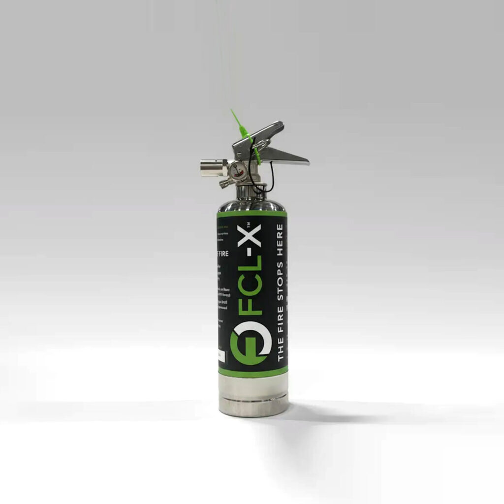 Close-up of a CO2 fire extinguisher with regulator, gauge, and a green safety pin/padlock attached to the valve