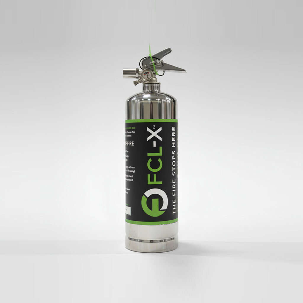 Metal fire extinguisher with pressure gauge, nozzle and hose, standing upright on a white surface with a green accent band on the canister period
